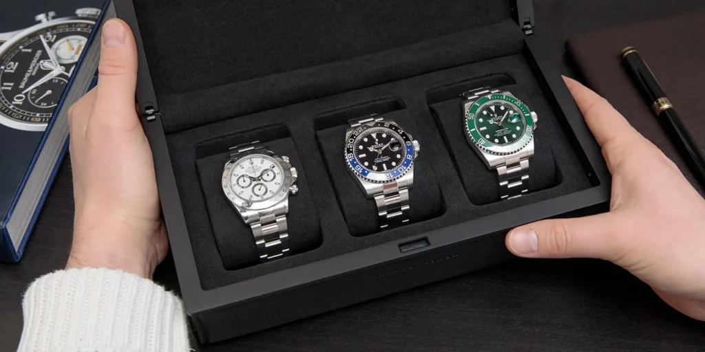 Investir dans les montres : trois Rolex emblématiques (Daytona, GMT-Master II et Submariner) présentées dans un écrin, illustrant des modèles considérés comme des montres valeur sûre pour un investissement horloger.