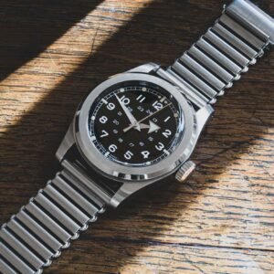 marque Serica modèle 4512 posé sur une table en bois, montrant son cadran noir épuré et son bracelet en acier inspiré des montres militaires.